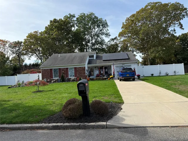 View of front of house featuring roof mounted solar panels, driveway, roof with shingles, brick siding, and a garage
