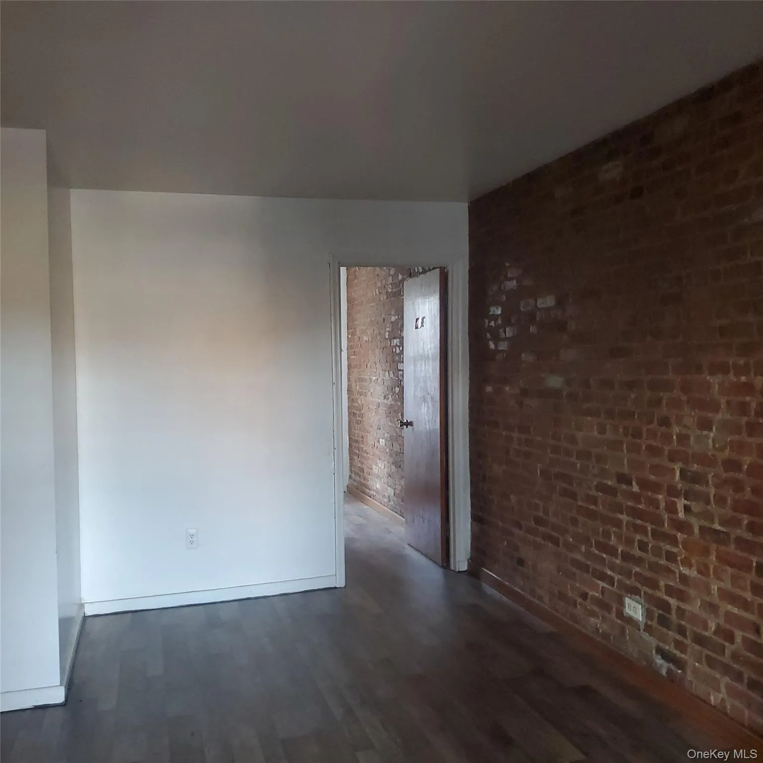 Unfurnished room with brick wall and dark wood finished floors Unfurnished room with brick wall and dark wood finished floors