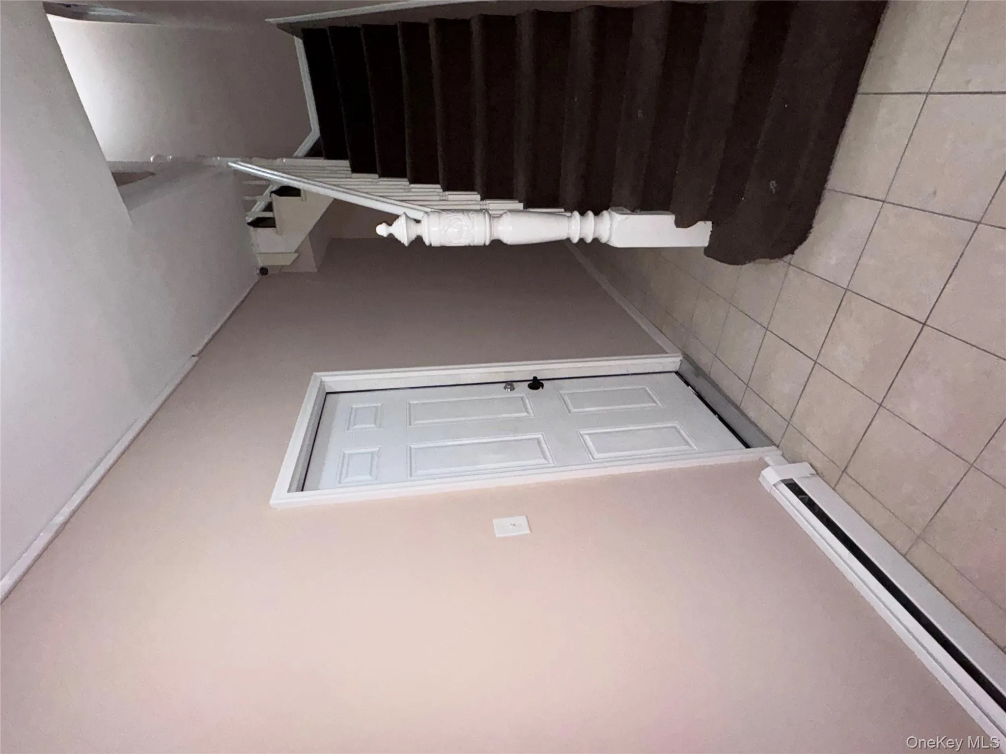 Stairway with a baseboard radiator and tile patterned flooring Stairway with a baseboard radiator and tile patterned flooring