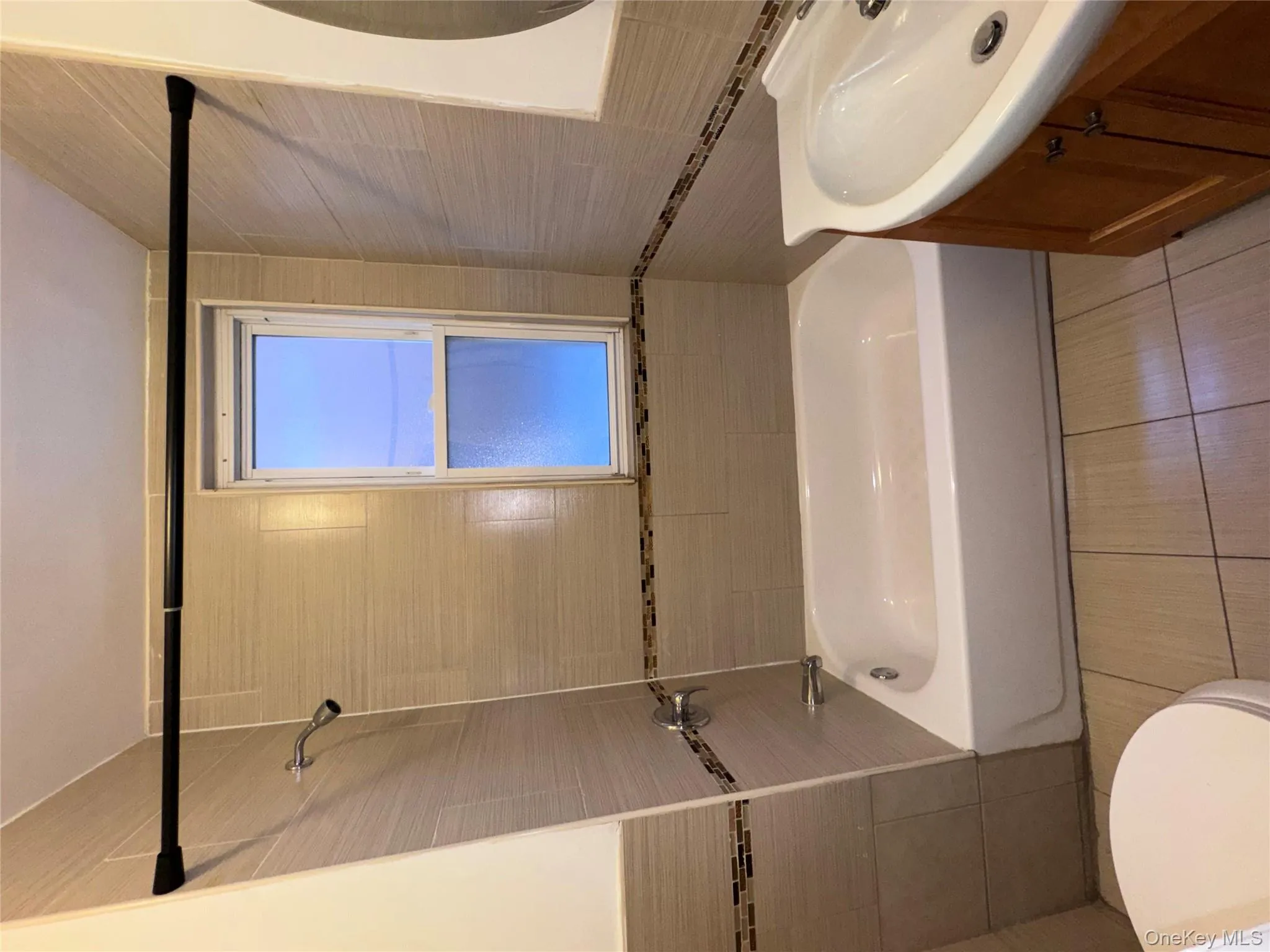 Bathroom featuring tile walls, vanity, bathing tub / shower combination, and light tile patterned floors Bathroom featuring tile walls, vanity, bathing tub / shower combination, and light tile patterned floors