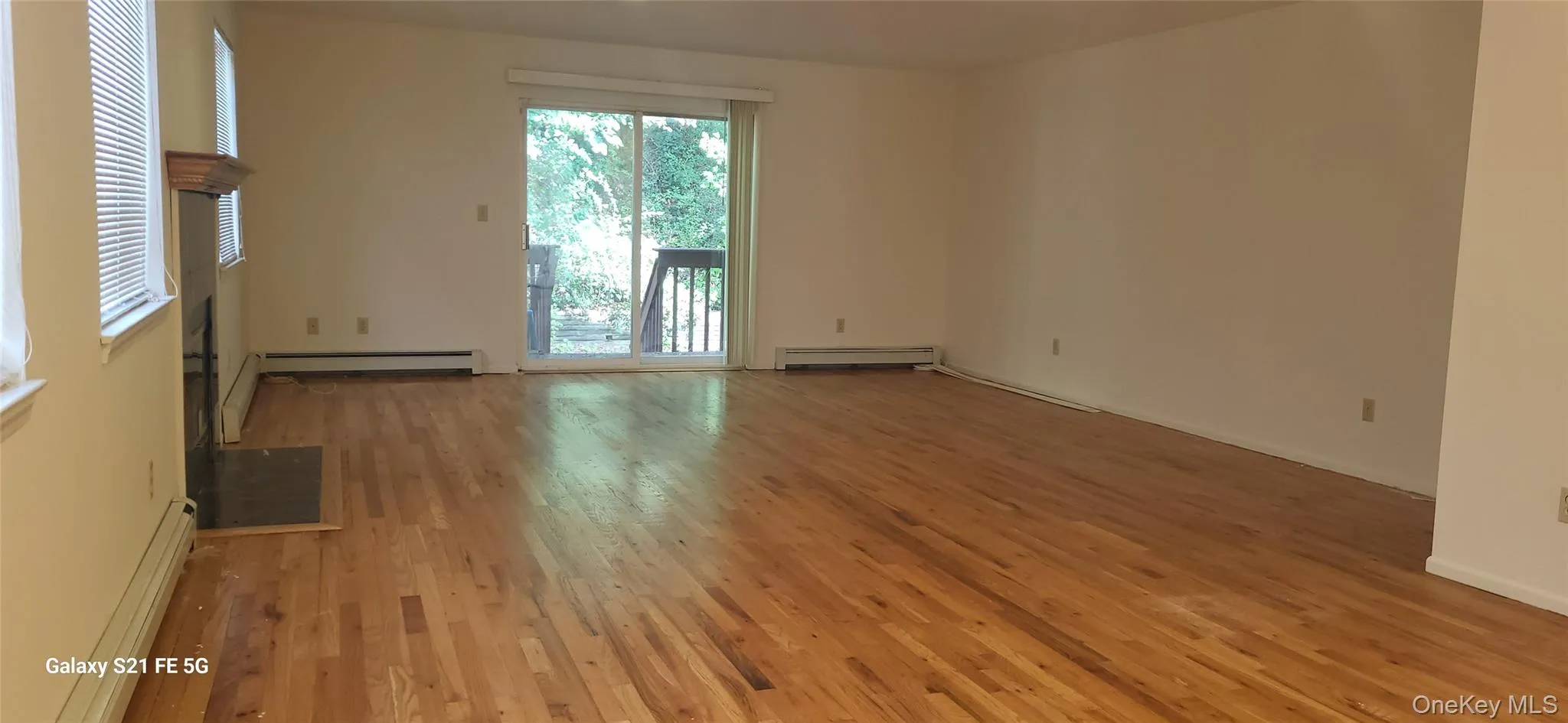 Empty room featuring light wood finished floors, baseboard heating, and a baseboard heating unit Empty room featuring light wood finished floors, baseboard heating, and a baseboard heating unit