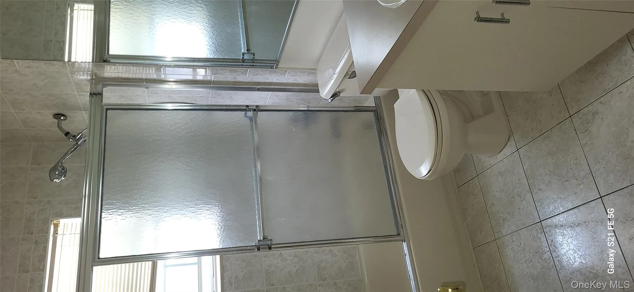 Full bath featuring vanity, combined bath / shower with glass door, and light tile patterned floors Full bath featuring vanity, combined bath / shower with glass door, and light tile patterned floors