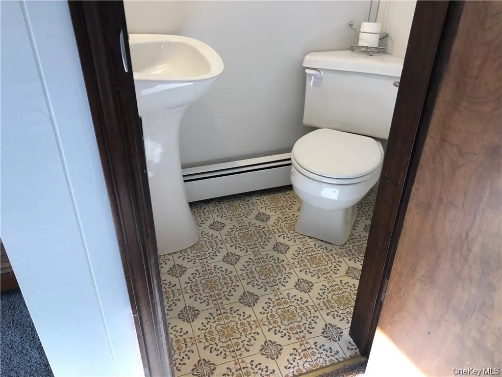 Half bath featuring baseboard heating and tile patterned floors Half bath featuring baseboard heating and tile patterned floors