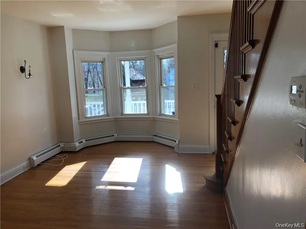 Unfurnished Living Room wood finished floors, stairs, and a baseboard radiator Unfurnished Living Room wood finished floors, stairs, and a baseboard radiator