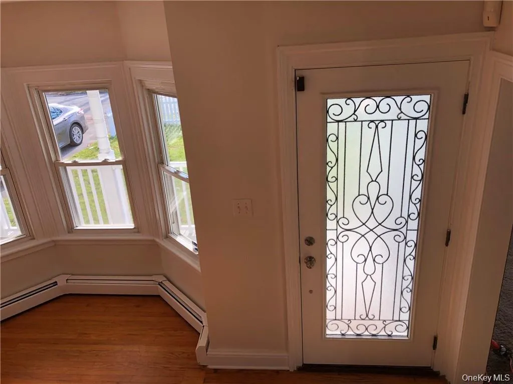 Entrance foyer featuring wood finished floors and a baseboard radiator Entrance foyer featuring wood finished floors and a baseboard radiator