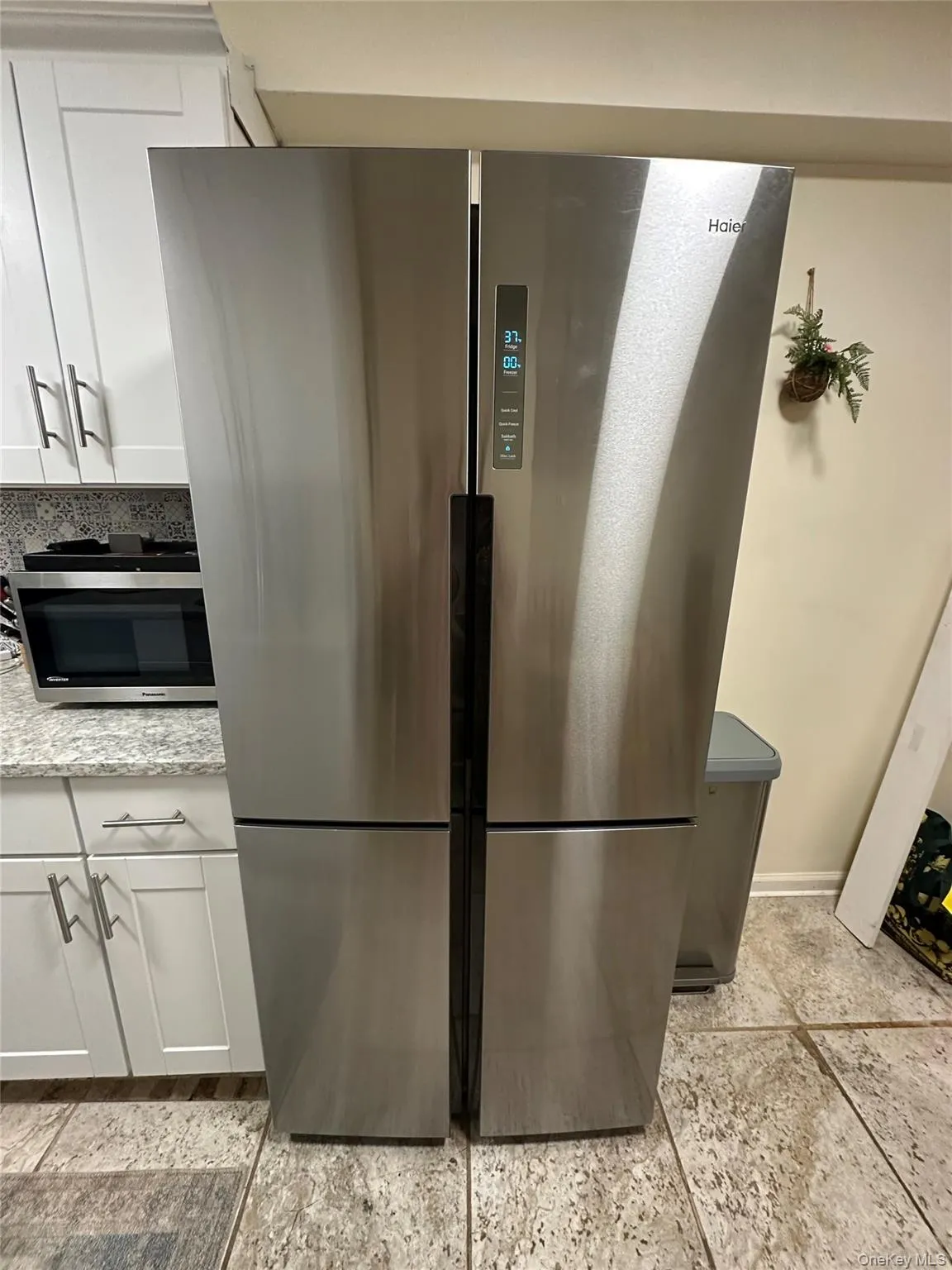 Kitchen view of white cabinetry, appliances with stainless steel finishes, and light stone countertops Kitchen view of white cabinetry, appliances with stainless steel finishes, and light stone countertops