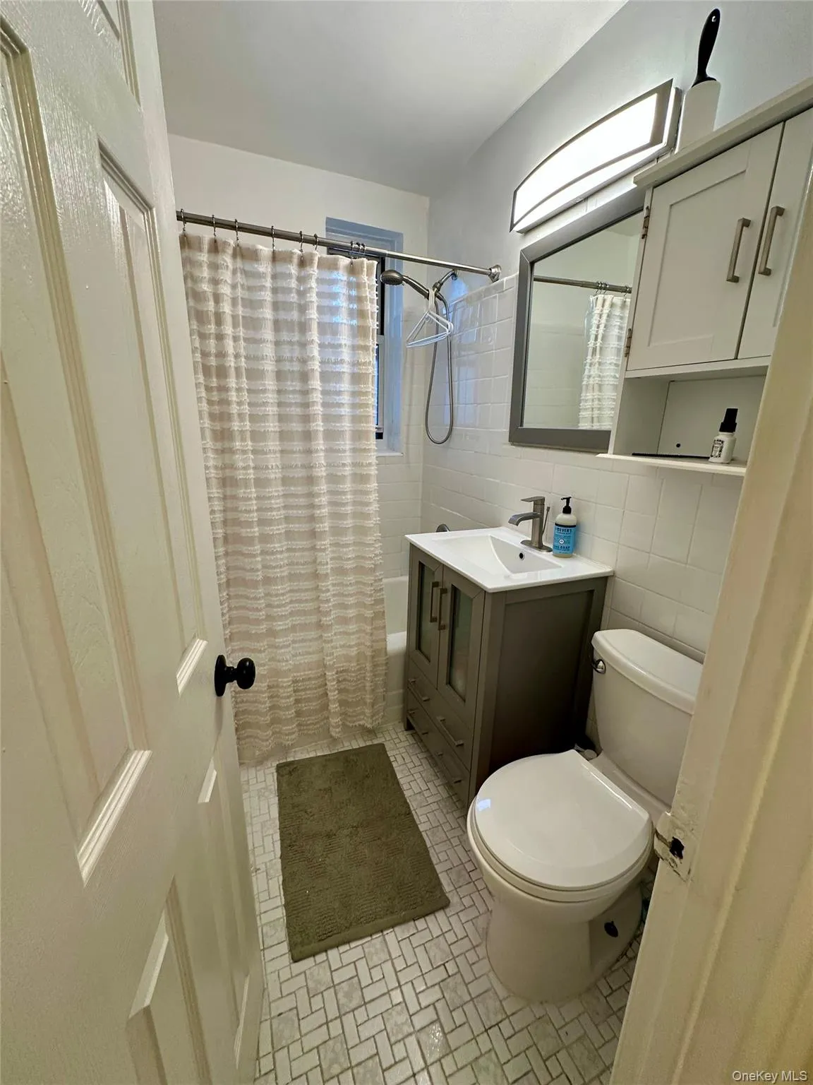 Bathroom with shower / bathtub combination with curtain, vanity, tile walls, and light tile patterned floors Bathroom with shower / bathtub combination with curtain, vanity, tile walls, and light tile patterned floors