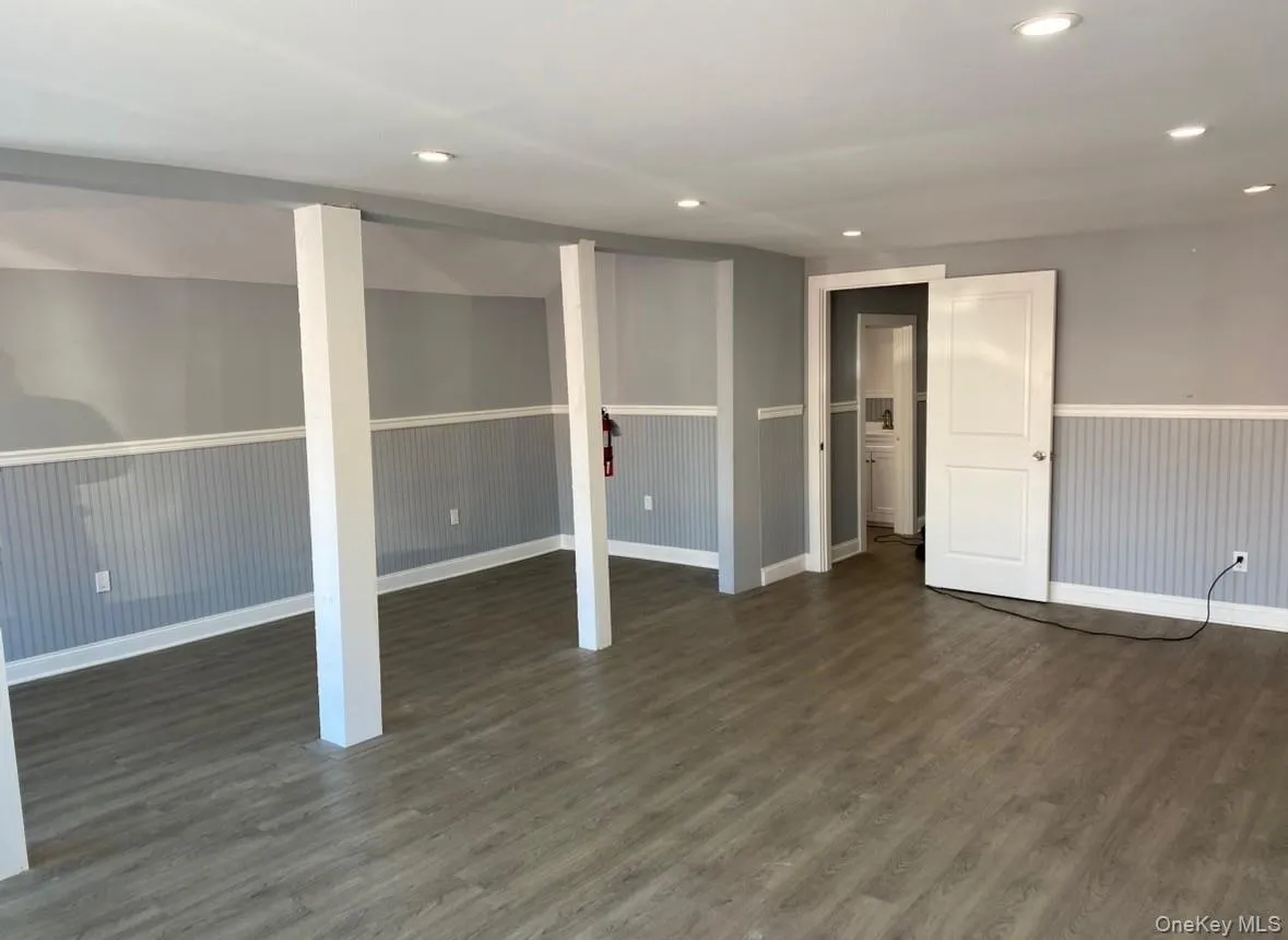 Finished basement featuring dark wood-style floors, recessed lighting, and a wainscoted wall Finished basement featuring dark wood-style floors, recessed lighting, and a wainscoted wall