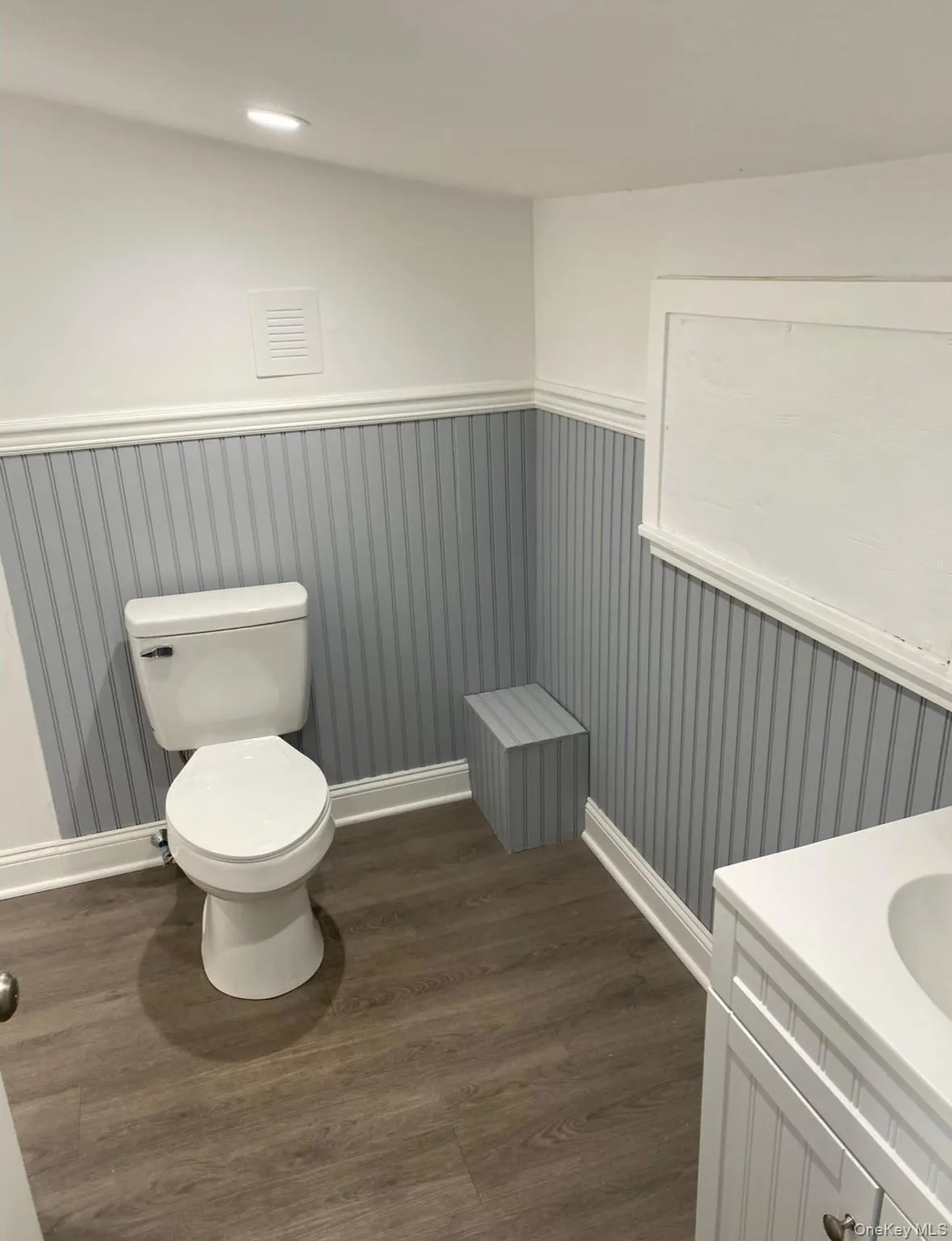 Half bath with dark wood-style flooring, vanity, and wainscoting Half bath with dark wood-style flooring, vanity, and wainscoting