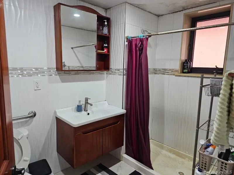 Bathroom with vanity, a stall shower, and tile walls Bathroom with vanity, a stall shower, and tile walls