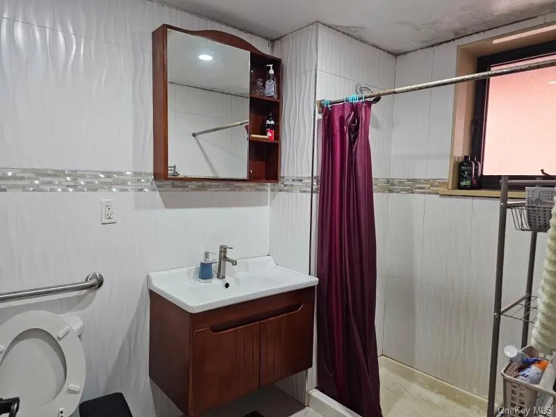 Bathroom featuring vanity, a shower stall, and tile walls Bathroom featuring vanity, a shower stall, and tile walls