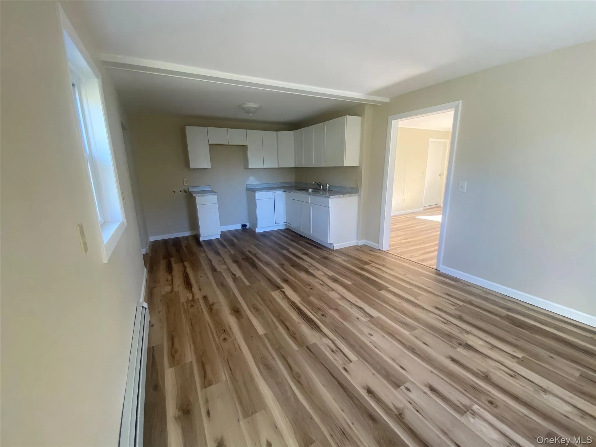 Unfurnished living room with a baseboard heating unit and dark wood-style flooring Unfurnished living room with a baseboard heating unit and dark wood-style flooring