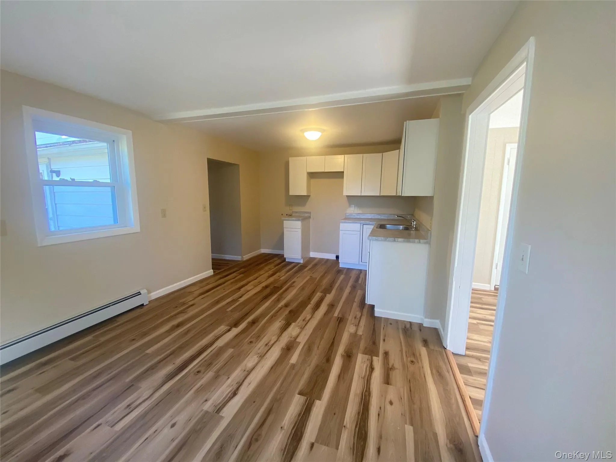 Unfurnished living room featuring dark wood-style floors and a baseboard heating unit Unfurnished living room featuring dark wood-style floors and a baseboard heating unit