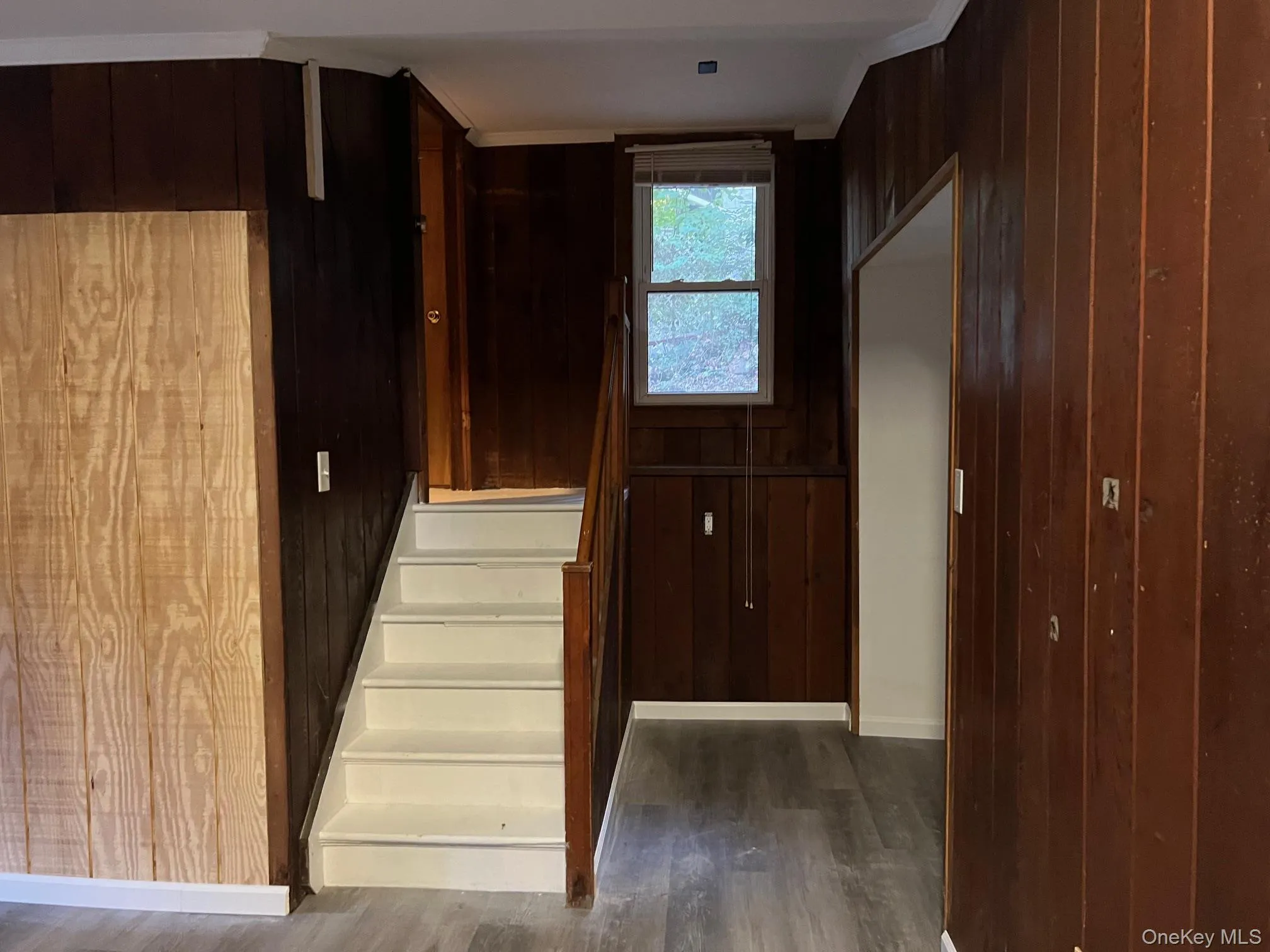 Hall featuring wood walls, dark wood finished floors, and stairway Hall featuring wood walls, dark wood finished floors, and stairway