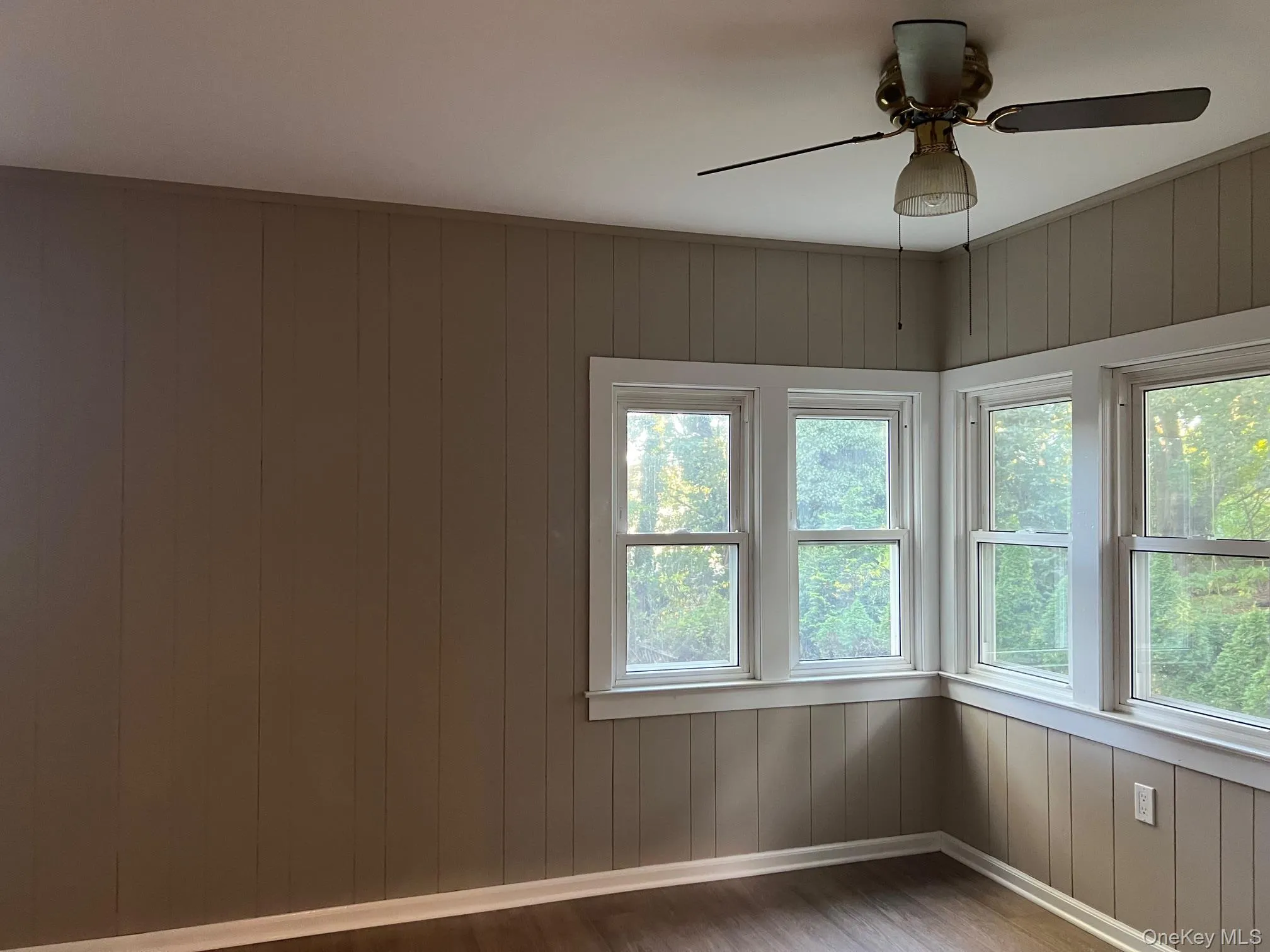 Spare room with wood finished floors, wood walls, plenty of natural light, and ceiling fan Spare room with wood finished floors, wood walls, plenty of natural light, and ceiling fan