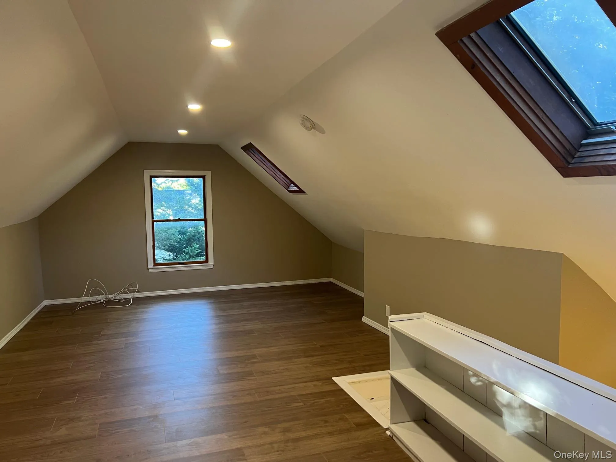 Bonus room with a skylight, dark wood-type flooring, vaulted ceiling, and recessed lighting Bonus room with a skylight, dark wood-type flooring, vaulted ceiling, and recessed lighting