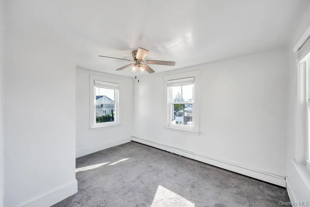Spare room featuring a baseboard heating unit, carpet flooring, healthy amount of natural light, and a ceiling fan Spare room featuring a baseboard heating unit, carpet flooring, healthy amount of natural light, and a ceiling fan