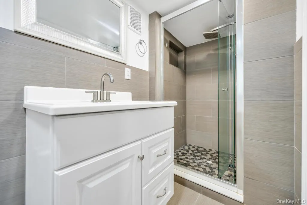 Full bath featuring tile walls, vanity, and a stall shower Full bath featuring tile walls, vanity, and a stall shower