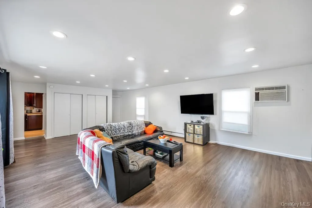 Living area featuring light wood-style floors, recessed lighting, a wall mounted AC, and a baseboard heating unit Living area featuring light wood-style floors, recessed lighting, a wall mounted AC, and a baseboard heating unit