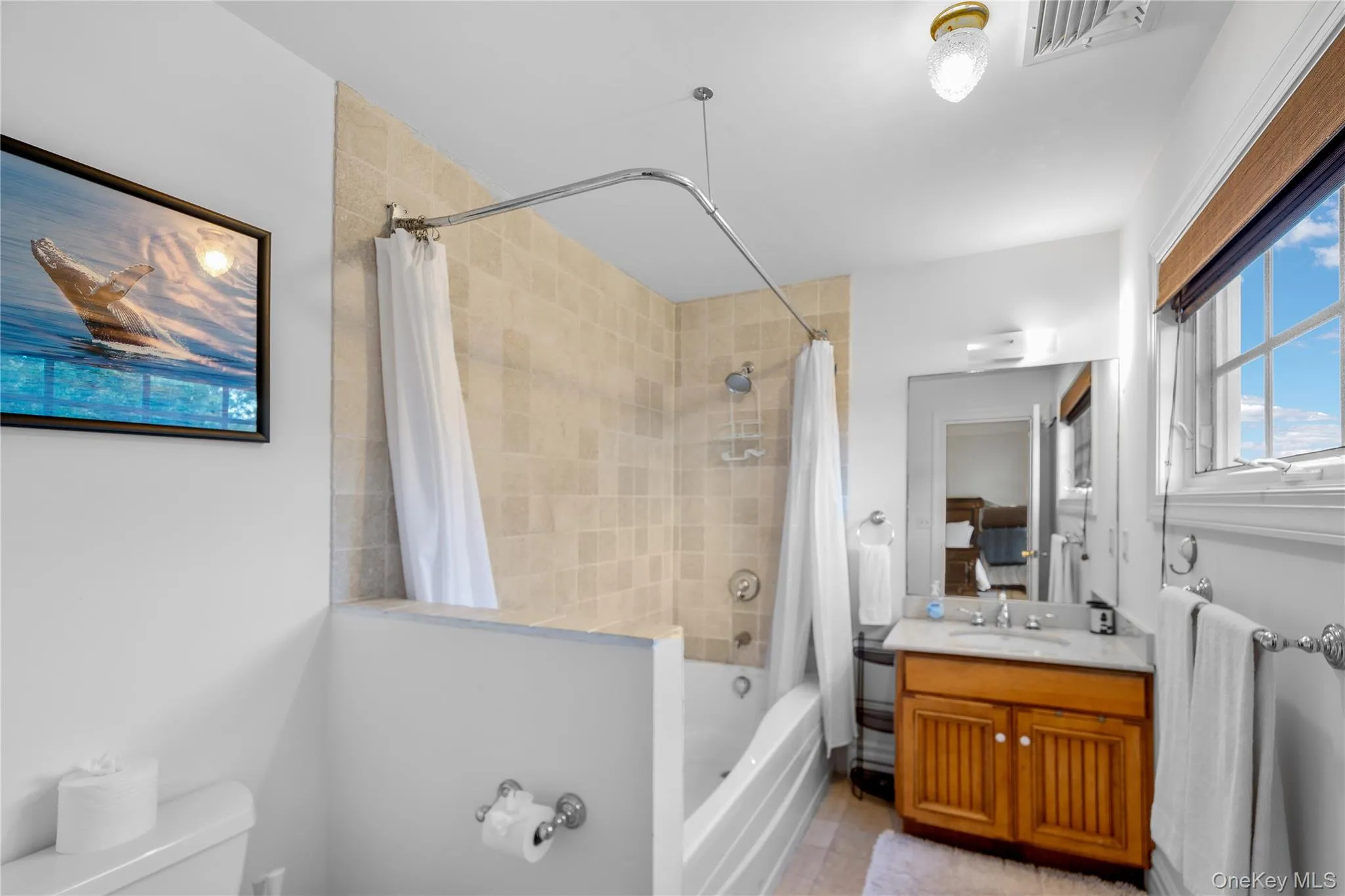 Bathroom featuring shower / bath combo, vanity, and light tile patterned flooring Bathroom featuring shower / bath combo, vanity, and light tile patterned flooring