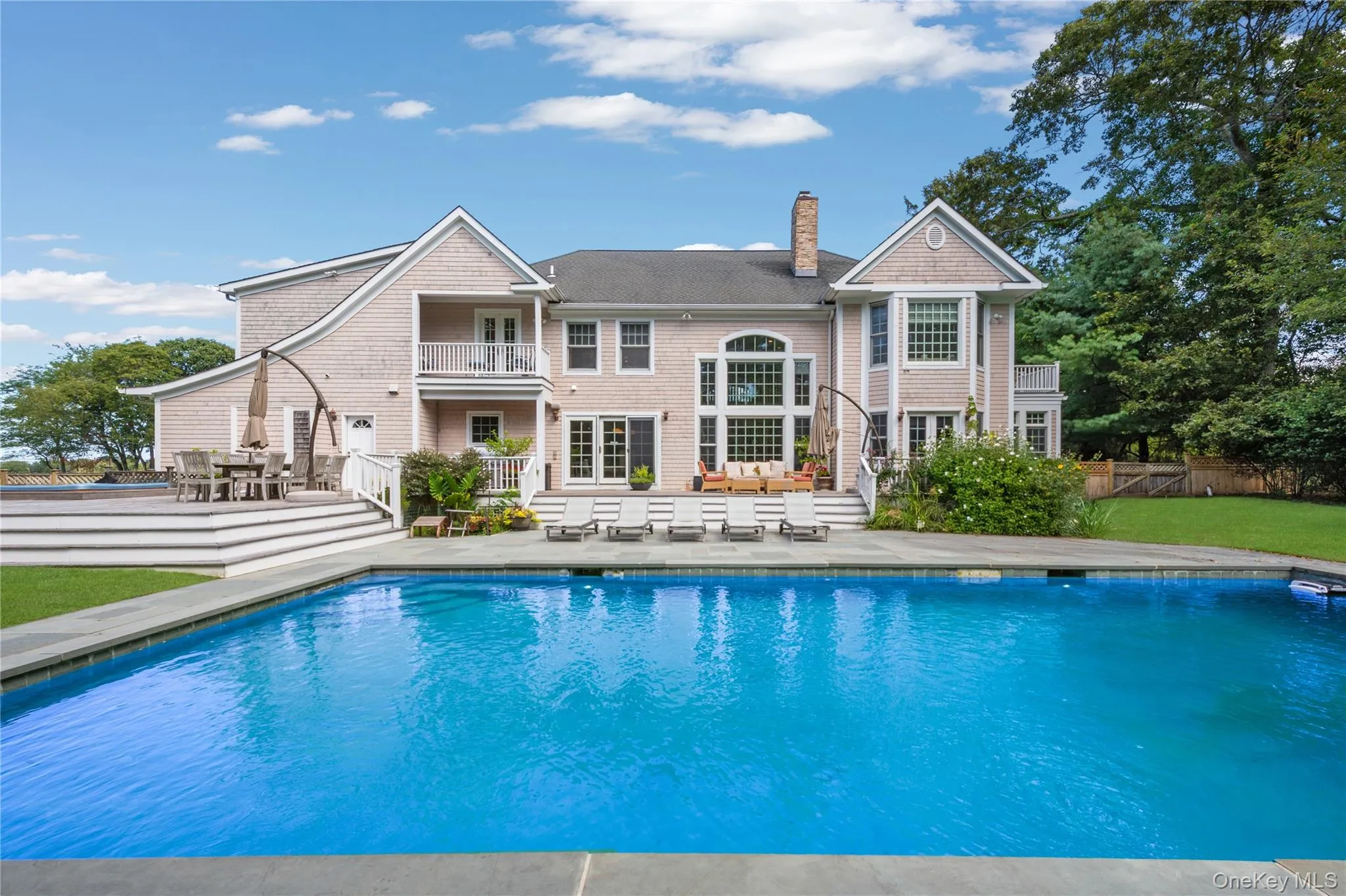 Back of house featuring a patio area, outdoor dining space, a chimney, and an outdoor pool Back of house featuring a patio area, outdoor dining space, a chimney, and an outdoor pool