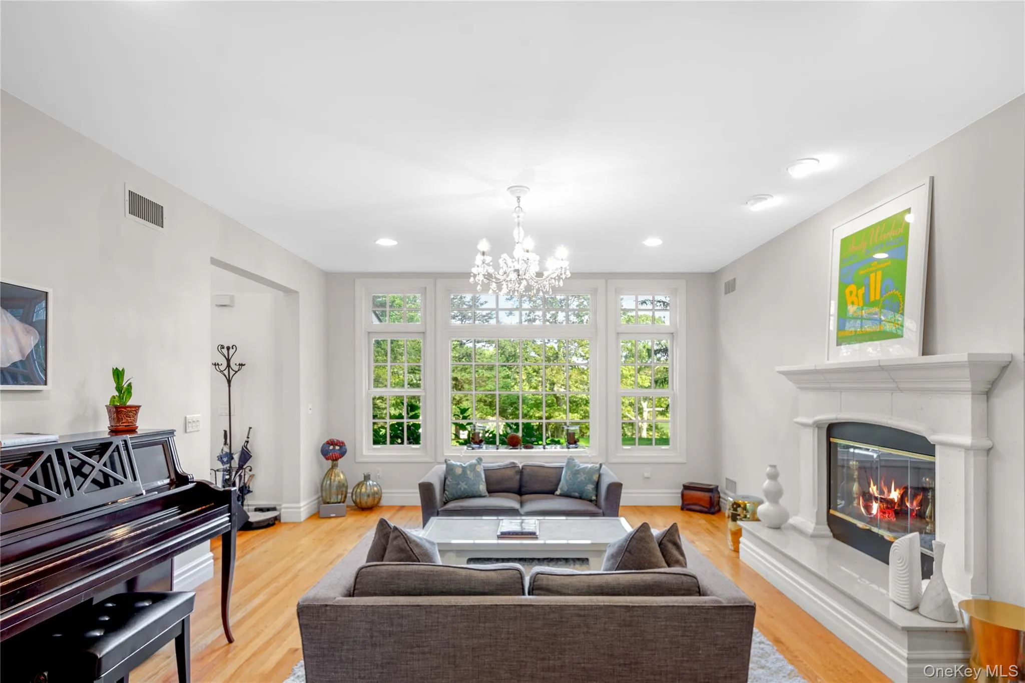 Living area with light wood-style flooring, a glass covered fireplace, recessed lighting, and a chandelier Living area with light wood-style flooring, a glass covered fireplace, recessed lighting, and a chandelier