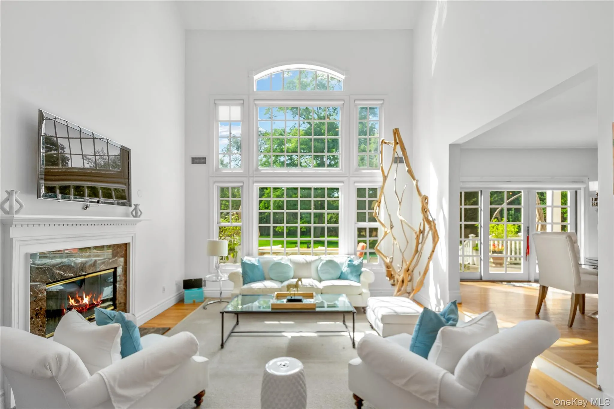 Living room featuring a high ceiling, wood finished floors, and a fireplace Living room featuring a high ceiling, wood finished floors, and a fireplace