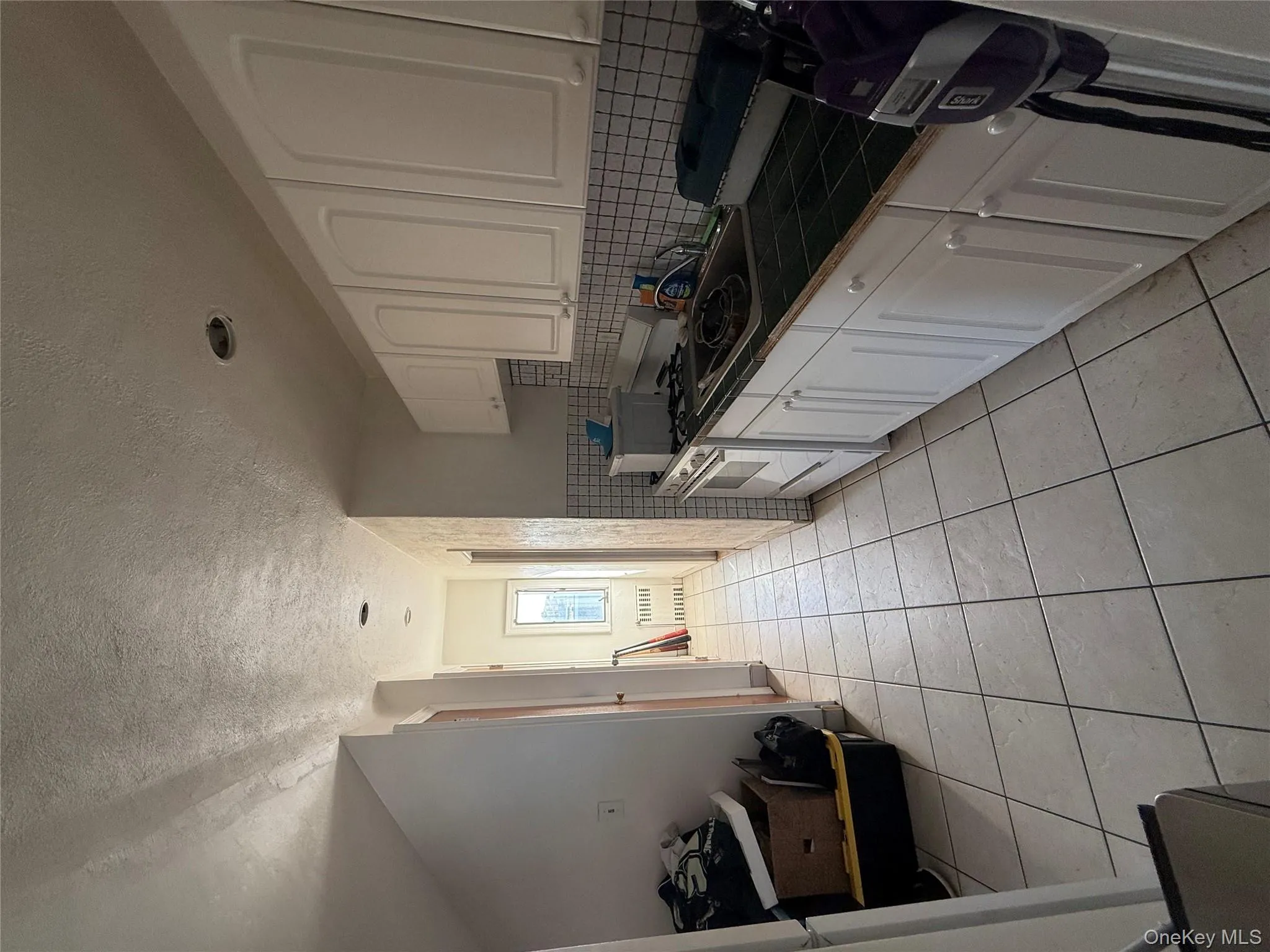Kitchen with tile countertops, a textured ceiling, white cabinets, stove, and tasteful backsplash Kitchen with tile countertops, a textured ceiling, white cabinets, stove, and tasteful backsplash