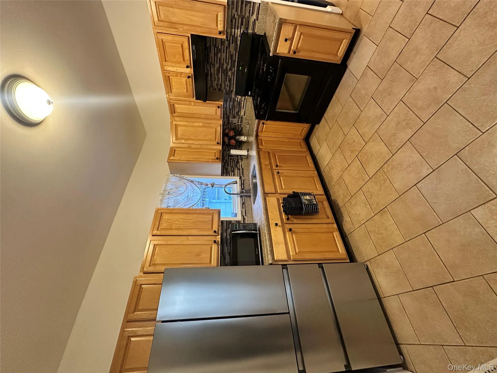 Kitchen with refrigerator, tasteful backsplash, range, and light tile patterned floors Kitchen with refrigerator, tasteful backsplash, range, and light tile patterned floors