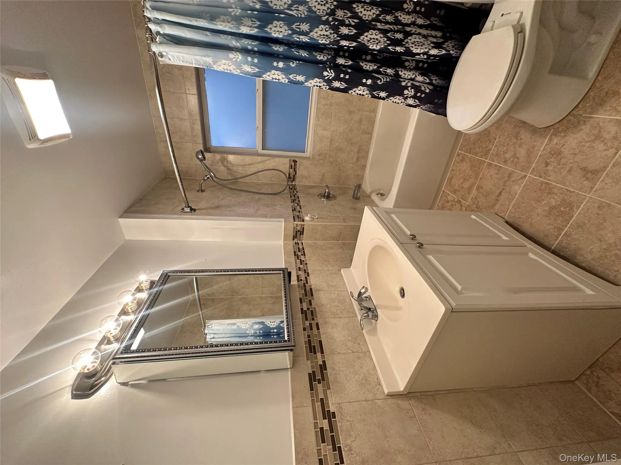 Full bath with vanity, tile walls, shower / tub combo, and light tile patterned flooring Full bath with vanity, tile walls, shower / tub combo, and light tile patterned flooring