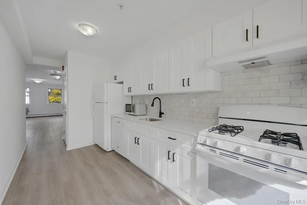 Kitchen with white appliances, backsplash, and white cabinets Kitchen with white appliances, backsplash, and white cabinets