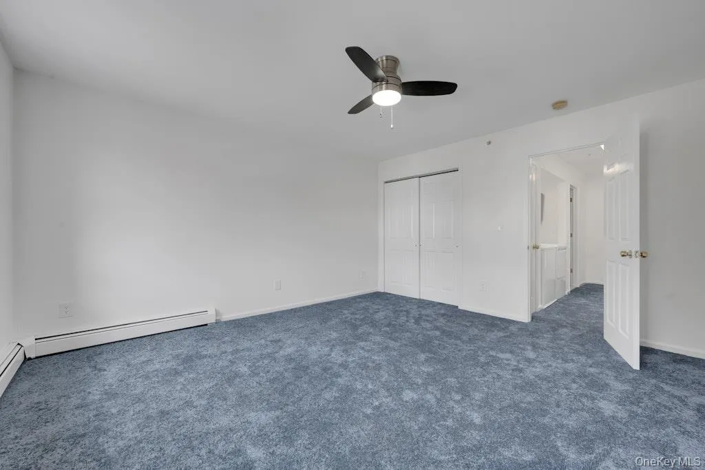 Unfurnished bedroom with dark colored carpet, a ceiling fan, and a closet Unfurnished bedroom with dark colored carpet, a ceiling fan, and a closet