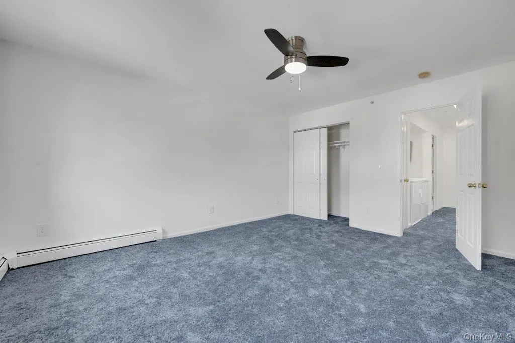 Unfurnished bedroom featuring carpet, a baseboard heating unit, ceiling fan, and a closet Unfurnished bedroom featuring carpet, a baseboard heating unit, ceiling fan, and a closet