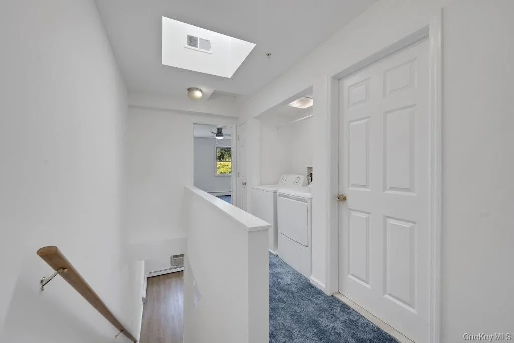 Hallway with an upstairs landing, a skylight, and washing machine and dryer Hallway with an upstairs landing, a skylight, and washing machine and dryer