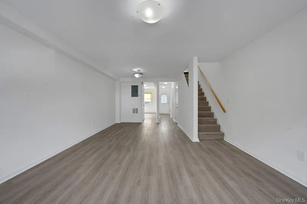 Unfurnished living room with stairway, wood finished floors, and electric panel Unfurnished living room with stairway, wood finished floors, and electric panel