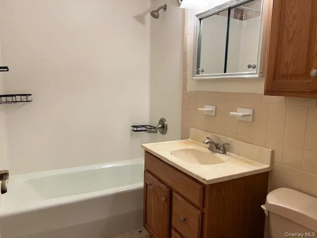 Full bathroom featuring vanity, tile walls, decorative backsplash, and shower / tub combination Full bathroom featuring vanity, tile walls, decorative backsplash, and shower / tub combination