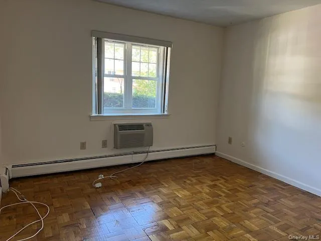 Empty room featuring a baseboard heating unit and a wall mounted AC Empty room featuring a baseboard heating unit and a wall mounted AC
