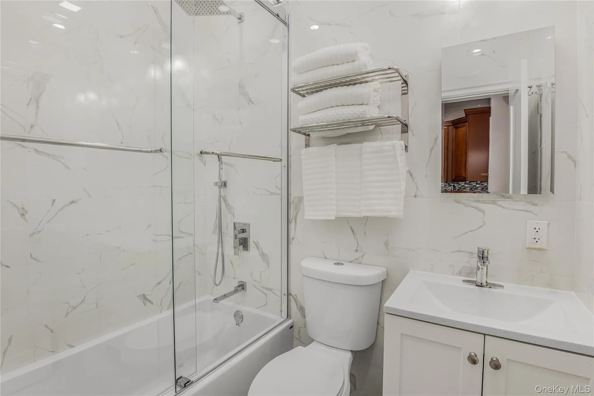 Bathroom featuring vanity, shower / bath combination with glass door, and tile walls Bathroom featuring vanity, shower / bath combination with glass door, and tile walls