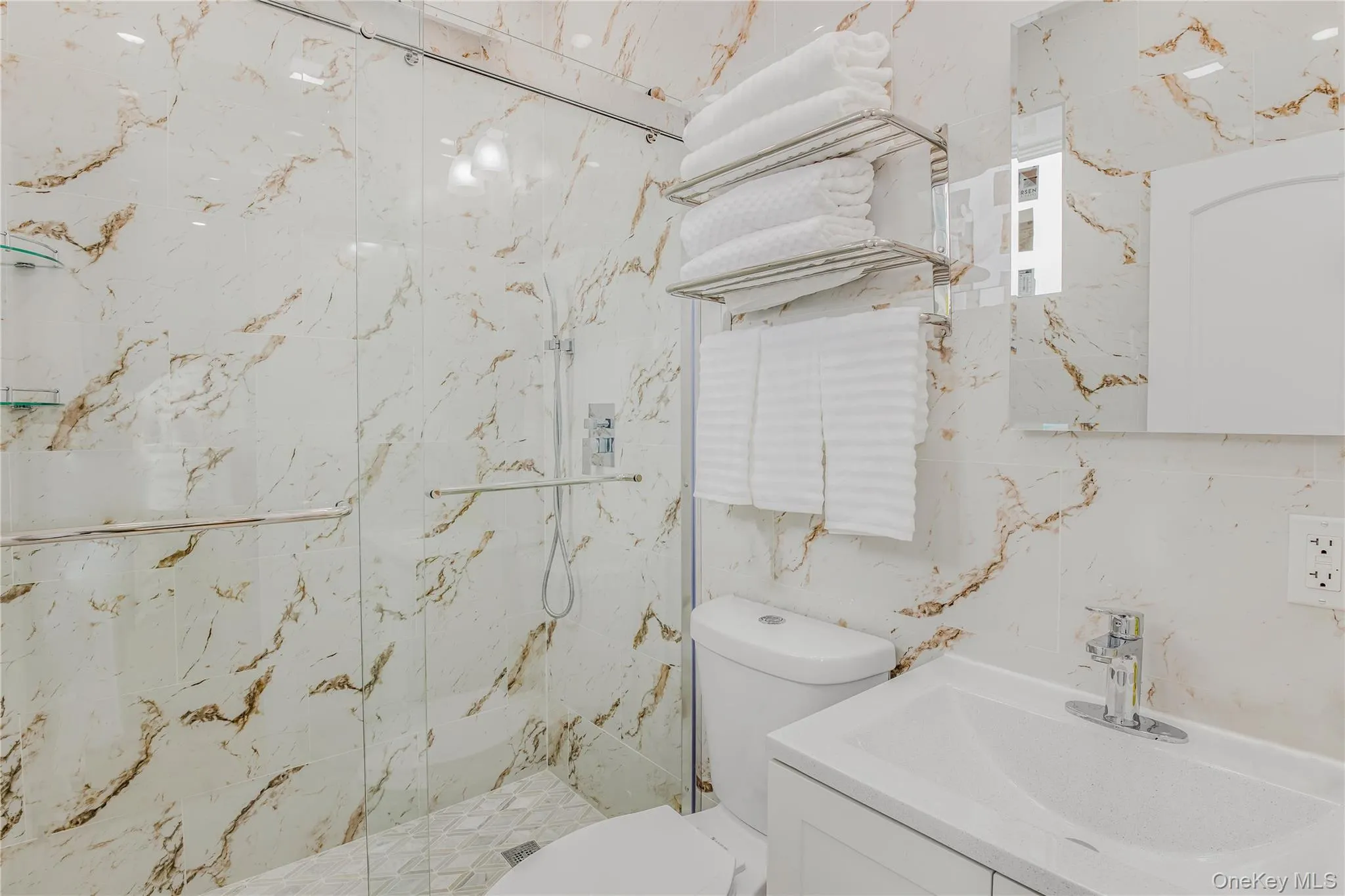 Bathroom with vanity, a marble finish shower, and tile walls Bathroom with vanity, a marble finish shower, and tile walls