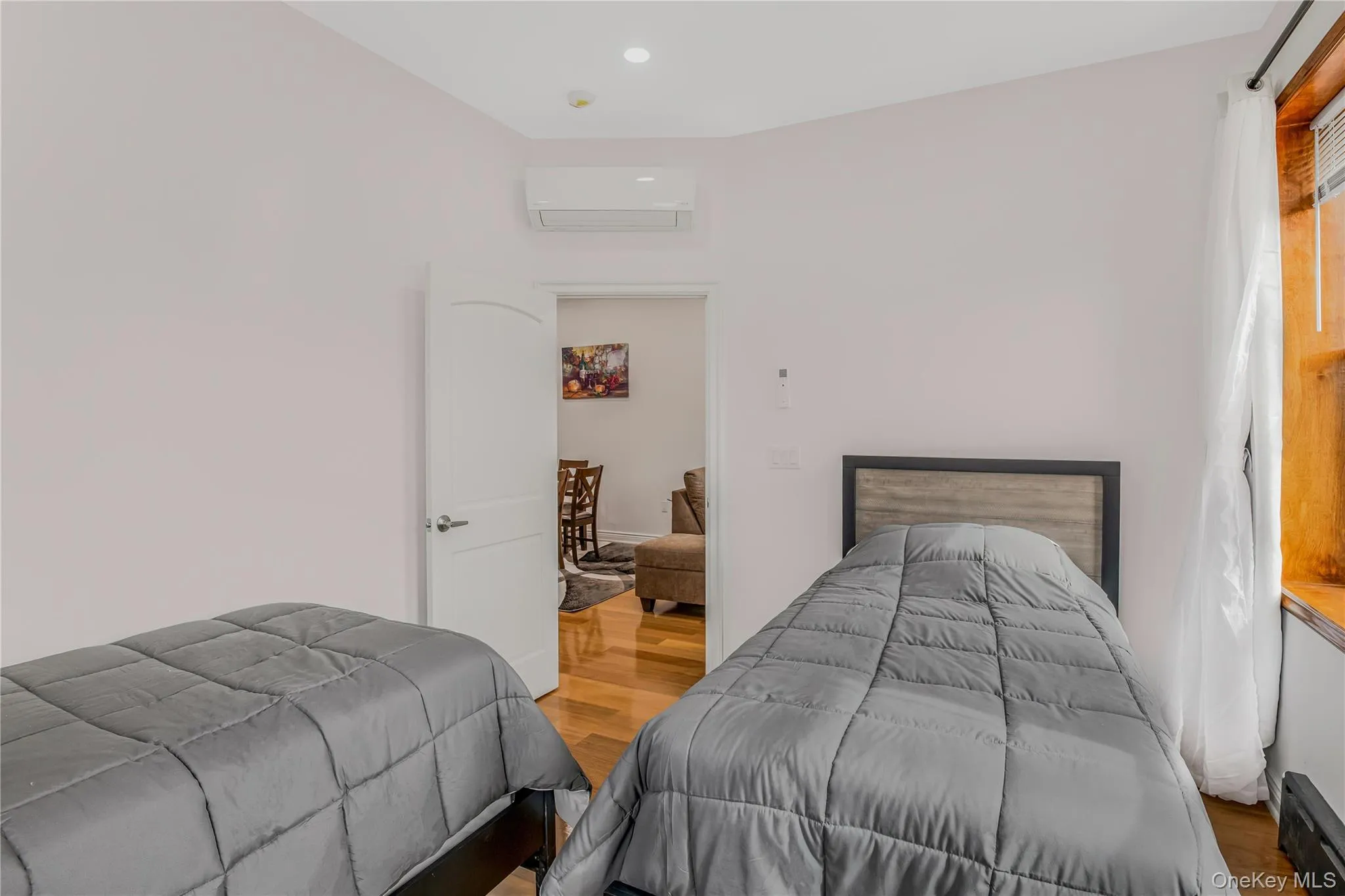 Bedroom #2 with wood finished floors, a baseboard radiator, a wall unit AC, and recessed lighting Bedroom #2 with wood finished floors, a baseboard radiator, a wall unit AC, and recessed lighting