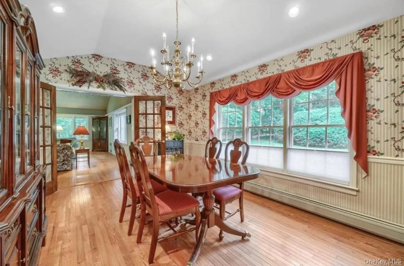 Dining room with wallpapered walls, light wood-style flooring, plenty of natural light, a baseboard heating unit, and lofted ceiling Dining room with wallpapered walls, light wood-style flooring, plenty of natural light, a baseboard heating unit, and lofted ceiling