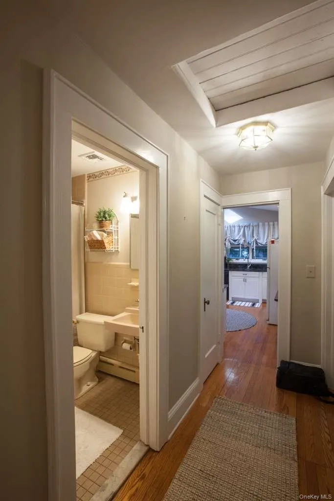 Hall with light wood-style flooring, a baseboard radiator, and tile walls Hall with light wood-style flooring, a baseboard radiator, and tile walls