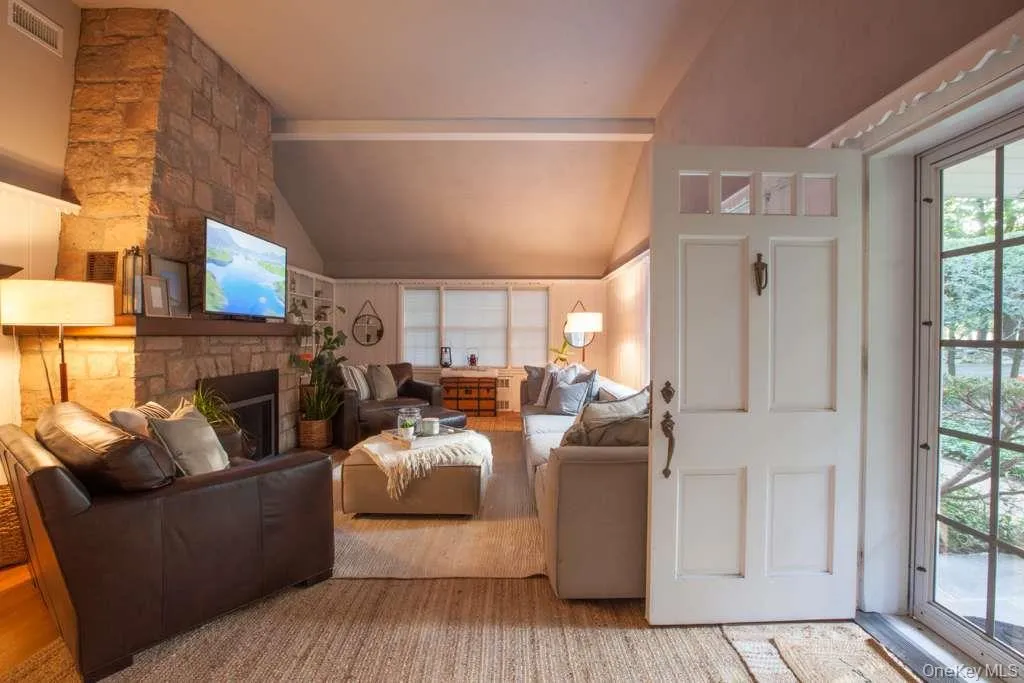 Living room featuring vaulted ceiling, a fireplace, and wood finished floors Living room featuring vaulted ceiling, a fireplace, and wood finished floors