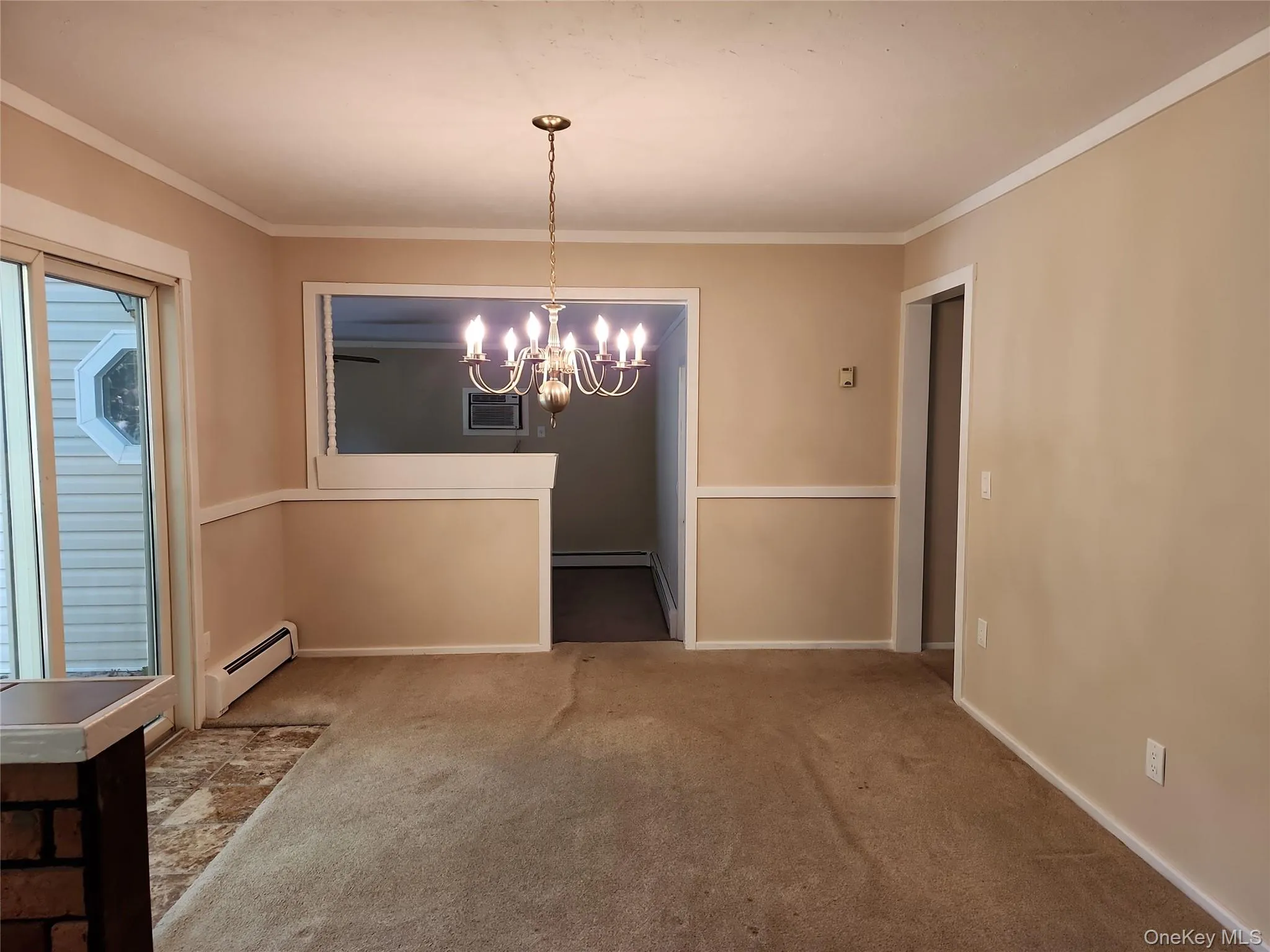 Unfurnished dining area featuring ornamental molding, carpet floors, a chandelier, and a baseboard radiator Unfurnished dining area featuring ornamental molding, carpet floors, a chandelier, and a baseboard radiator