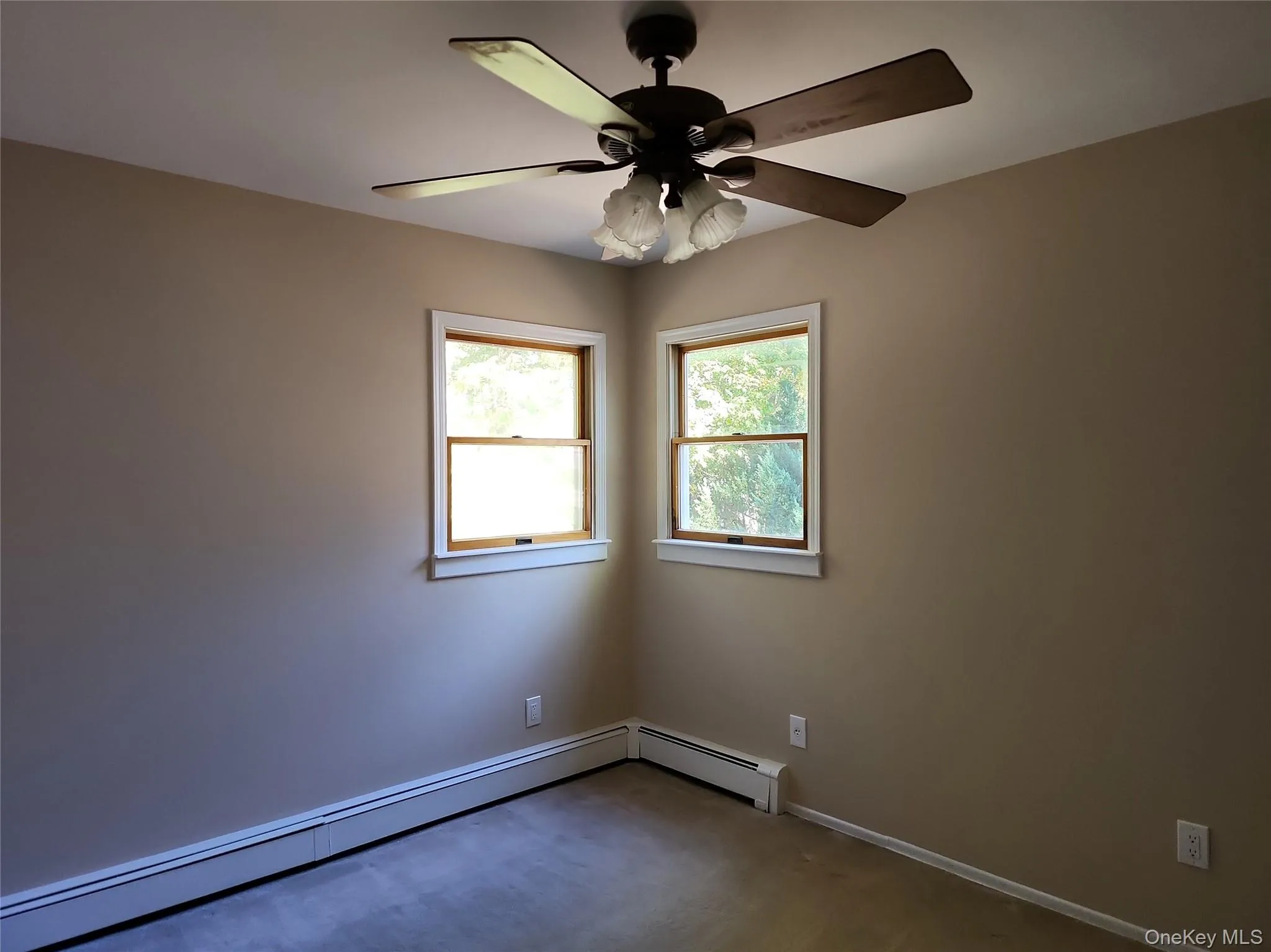Carpeted spare room featuring baseboard heating and a ceiling fan Carpeted spare room featuring baseboard heating and a ceiling fan