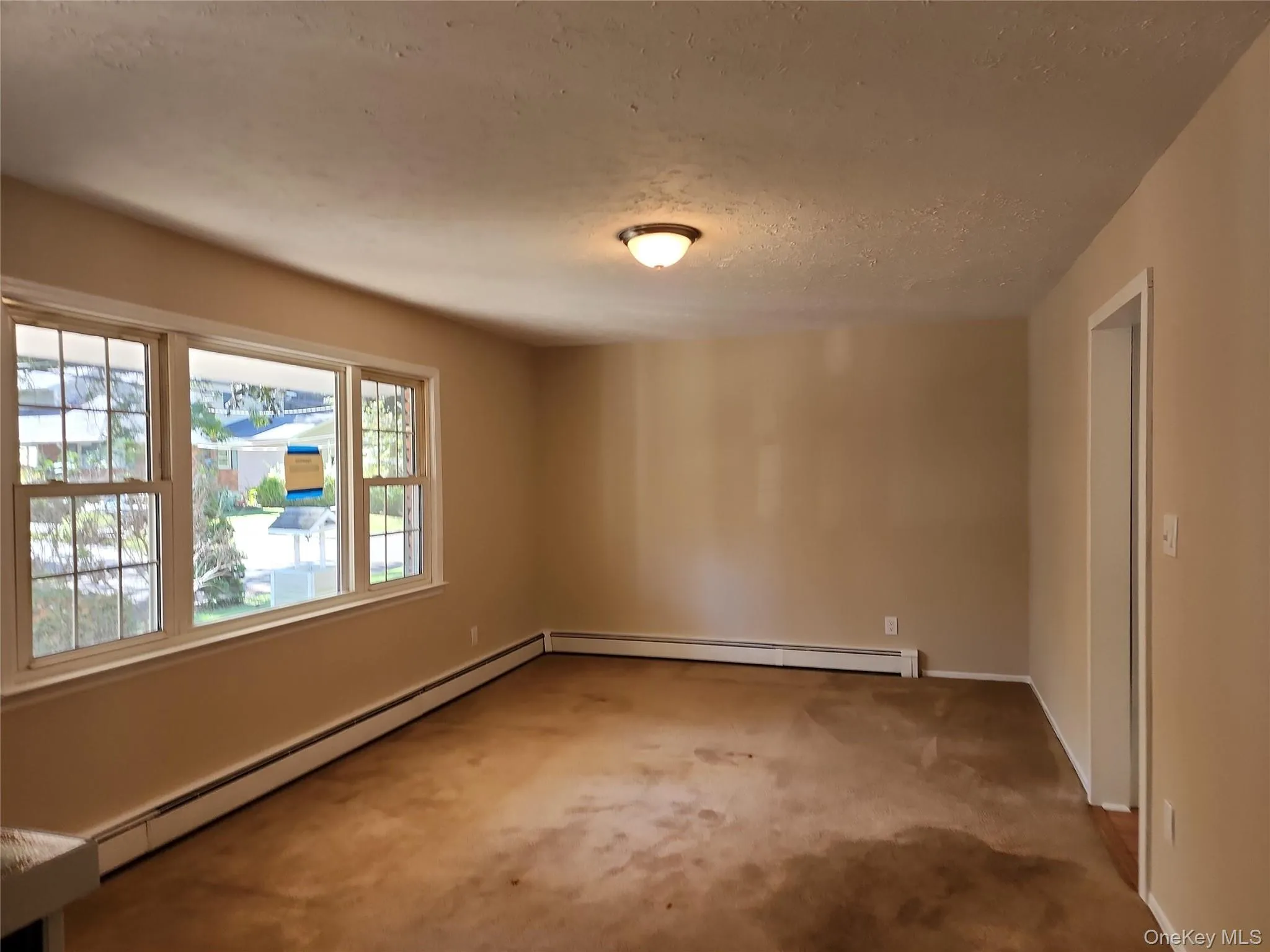 Unfurnished room featuring a baseboard heating unit, carpet, and a textured ceiling Unfurnished room featuring a baseboard heating unit, carpet, and a textured ceiling