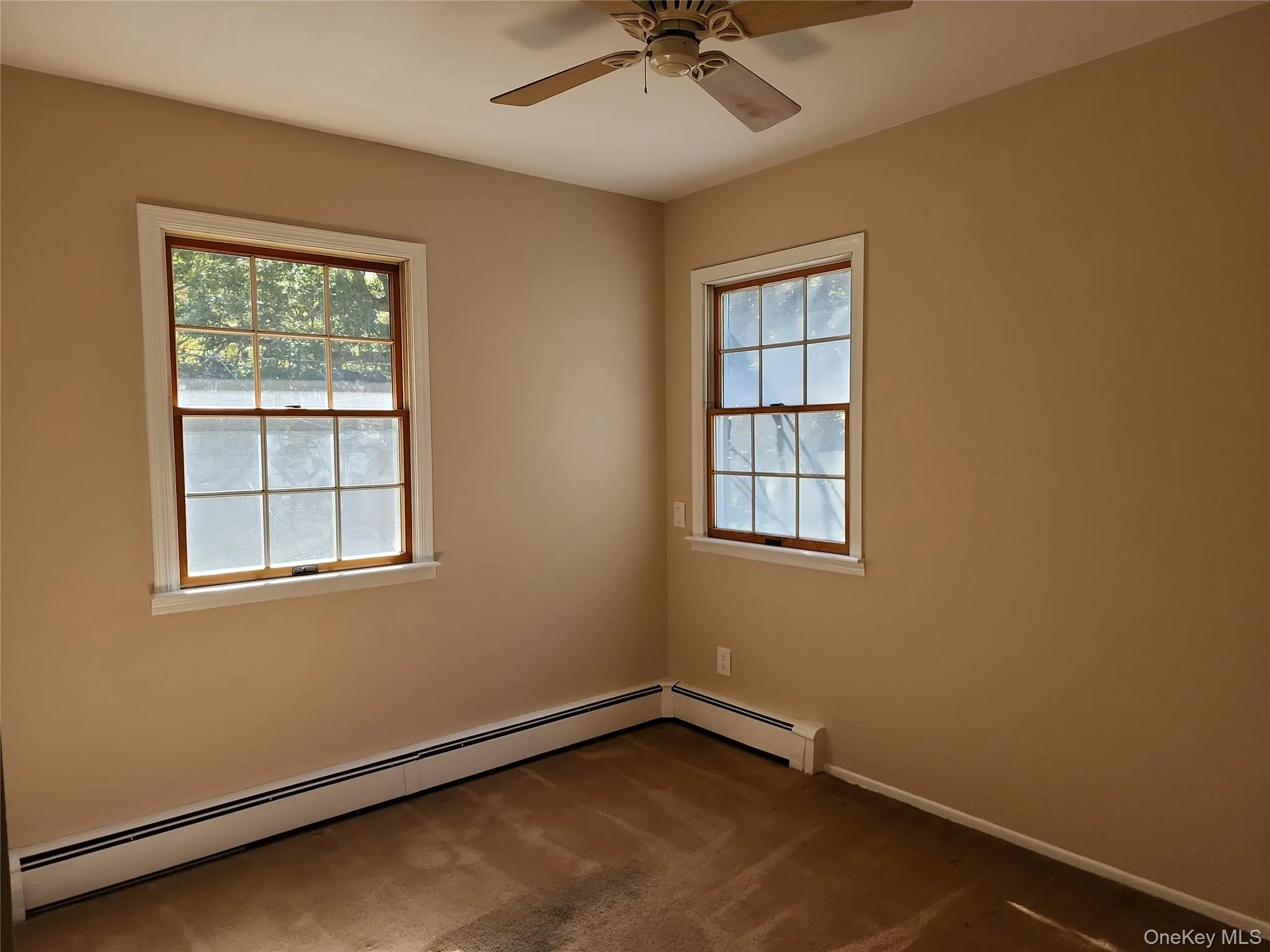 Empty room with a baseboard heating unit, carpet floors, and ceiling fan Empty room with a baseboard heating unit, carpet floors, and ceiling fan