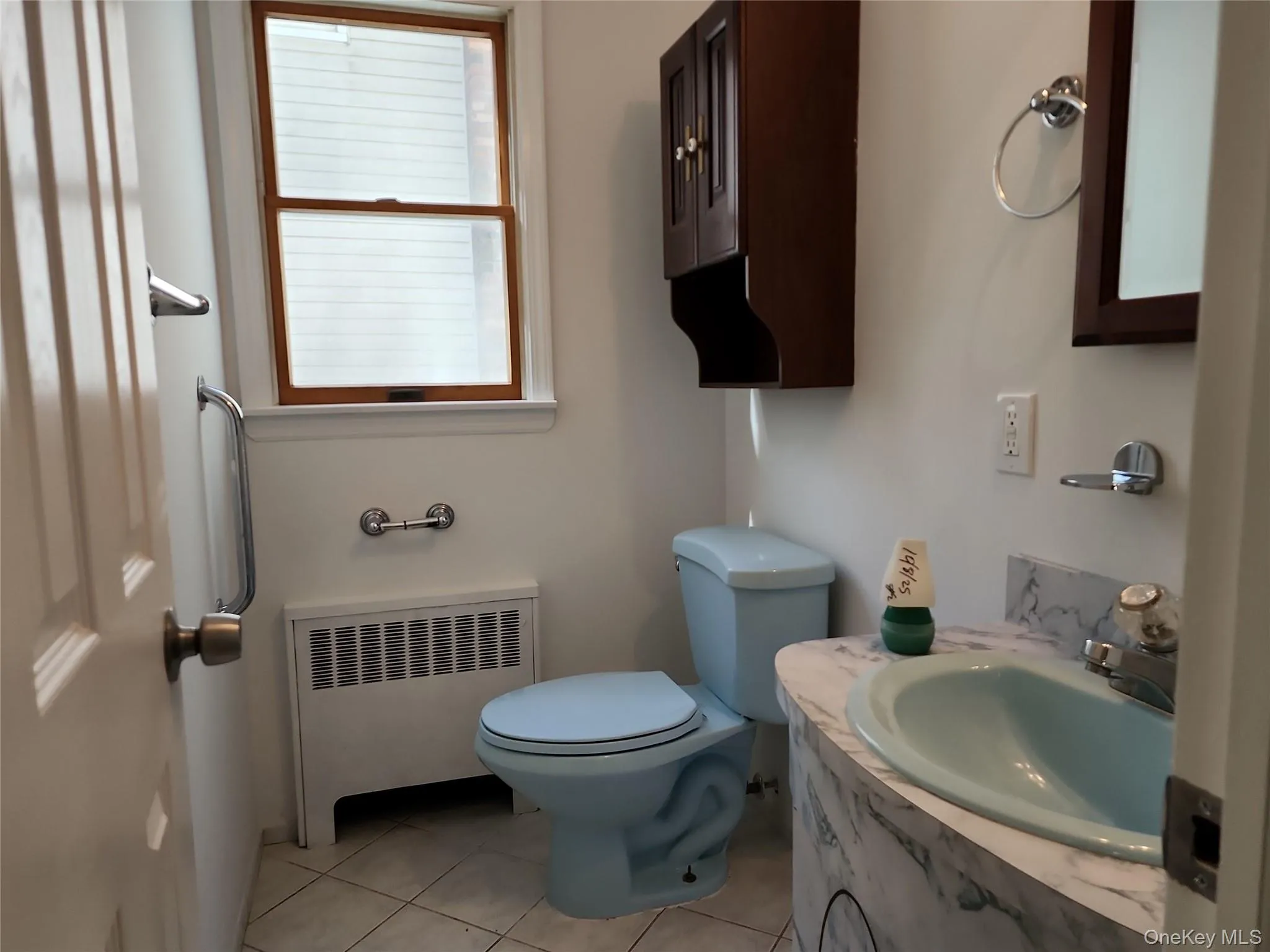 Half bath featuring radiator, vanity, and light tile patterned flooring Half bath featuring radiator, vanity, and light tile patterned flooring