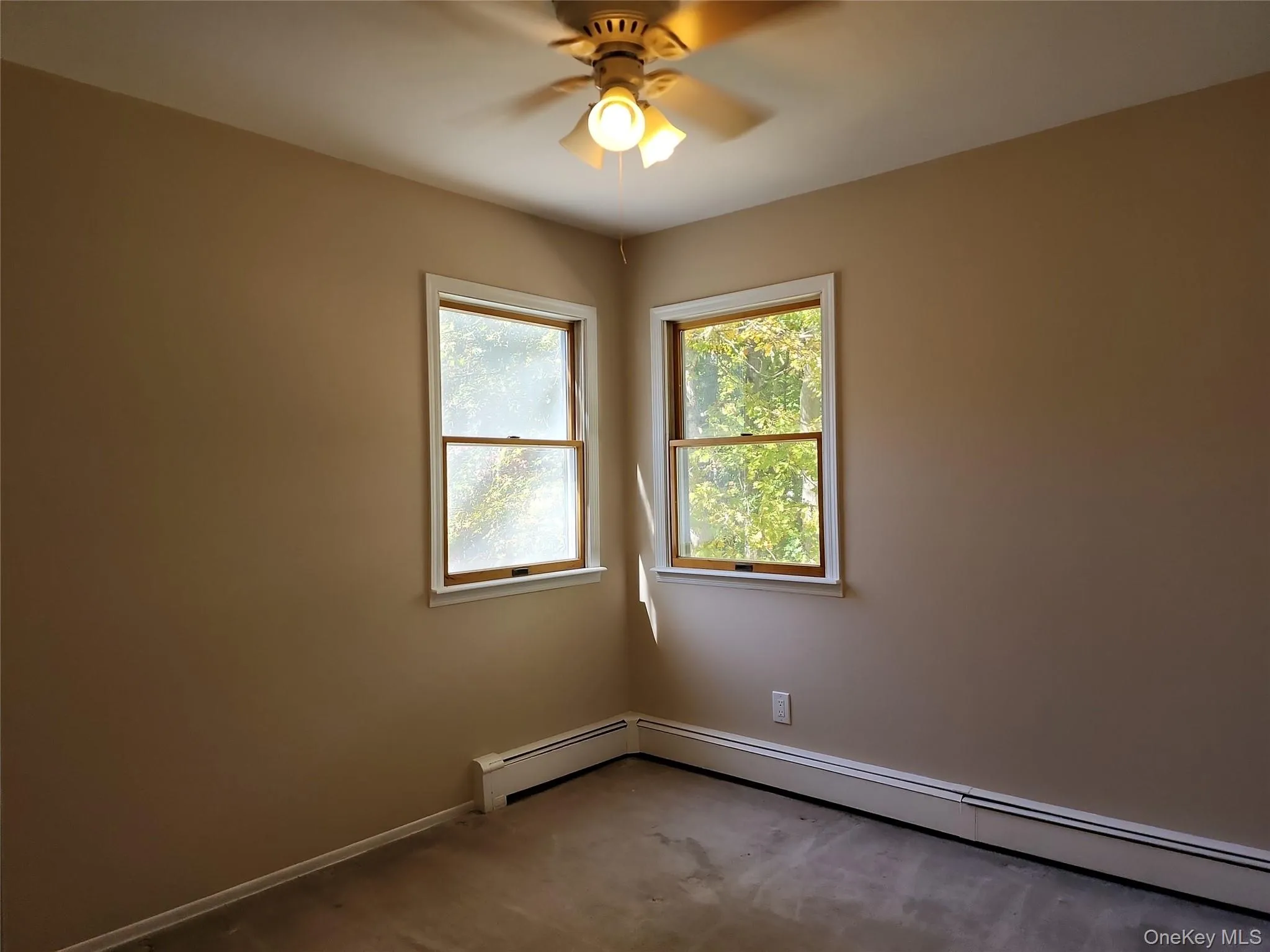 Carpeted empty room featuring a baseboard heating unit and a ceiling fan Carpeted empty room featuring a baseboard heating unit and a ceiling fan