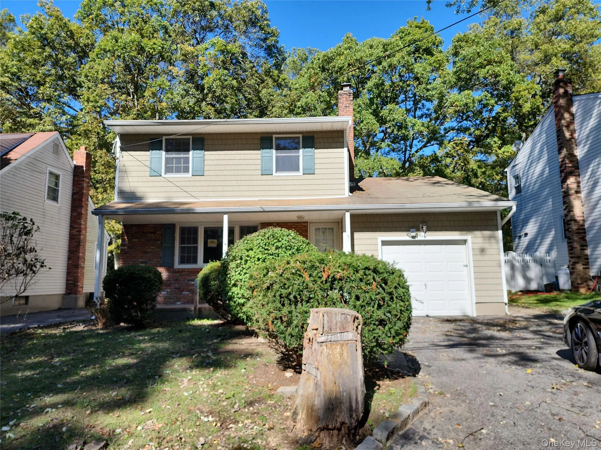 Traditional-style house featuring a garage, a chimney, asphalt driveway, a front yard, and covered porch Traditional-style house featuring a garage, a chimney, asphalt driveway, a front yard, and covered porch